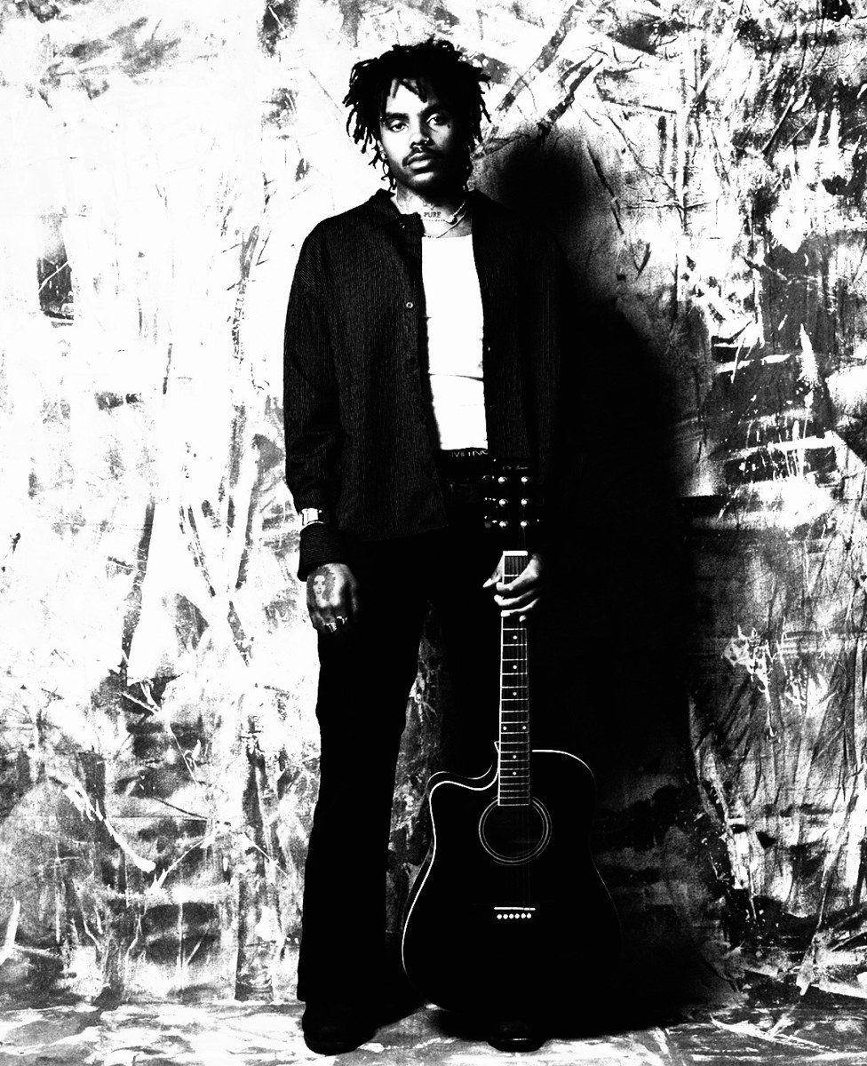 Carver Jones standing with an acoustic guitar, black and white portrait